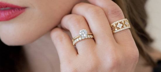 Close up photo of a woman's hand touching her face with diamond rings on multiple fingers.