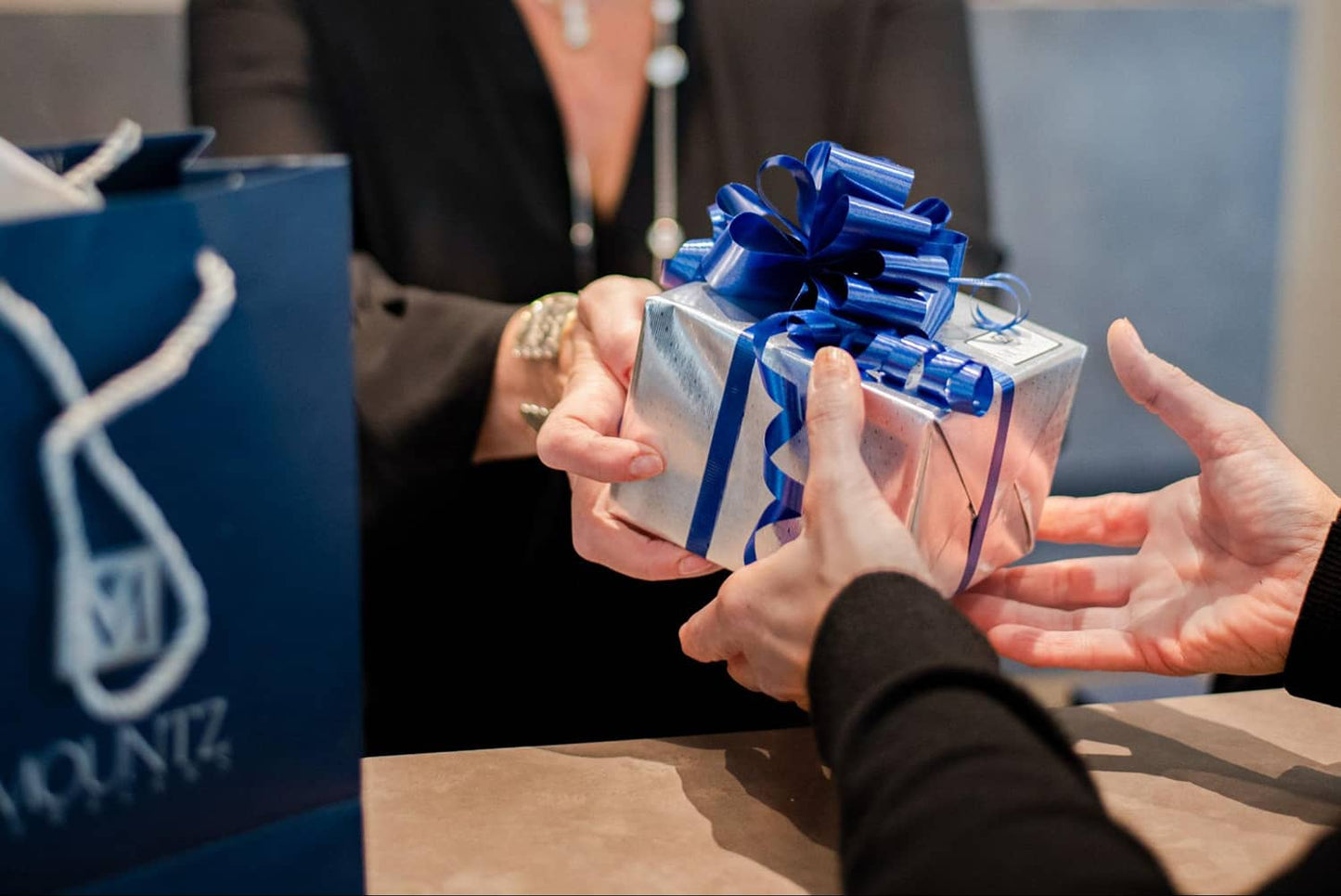 Salesperson handing customer gift box wrapped by Mountz