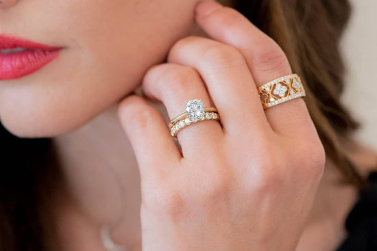Close up photo of woman's hand wearing 3 rings up against her chin