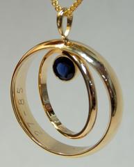 A beautiful pendent made from two weddings rings linked together and a blue sapphire