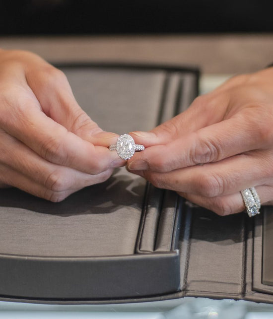Close up photo of 2 hands holding a diamond engagement ring